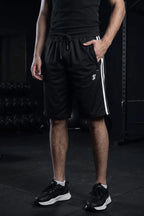 Man wearing black athletic shorts with white side stripes, rear view at the gym