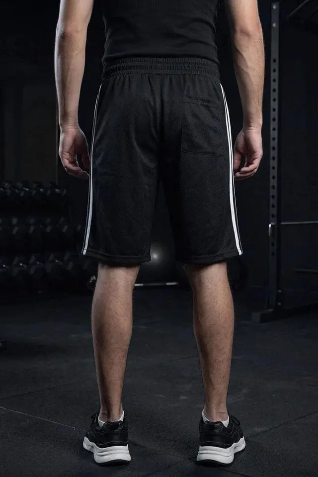 Man wearing black athletic shorts with white side stripes, rear view at the gym